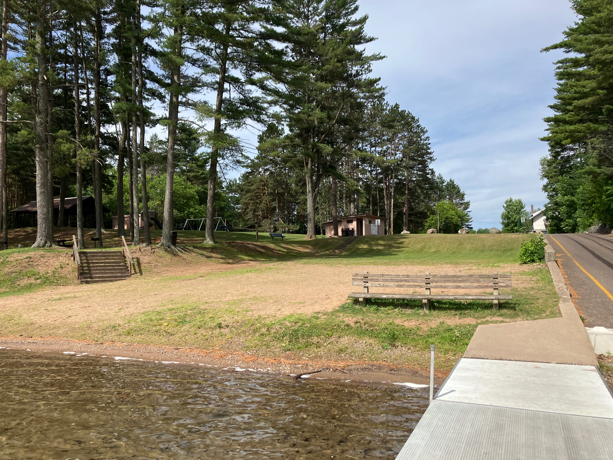 A sandy beach area with wooden docks on a clear Northwoods lake